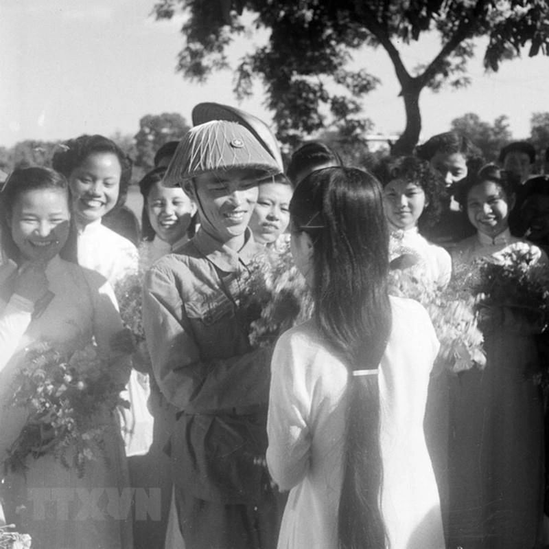 Thiếu tướng Vương Thừa Vũ, Tư lệnh Đại đoàn 308, Chủ tịch Ủy ban Quân chính Thành phố nhận hoa chúc mừng từ các nữ sinh trường Trưng Vương bên hồ Hoàn Kiếm trong ngày giải phóng Thủ đô. (Ảnh: Tư liệu TTXVN)